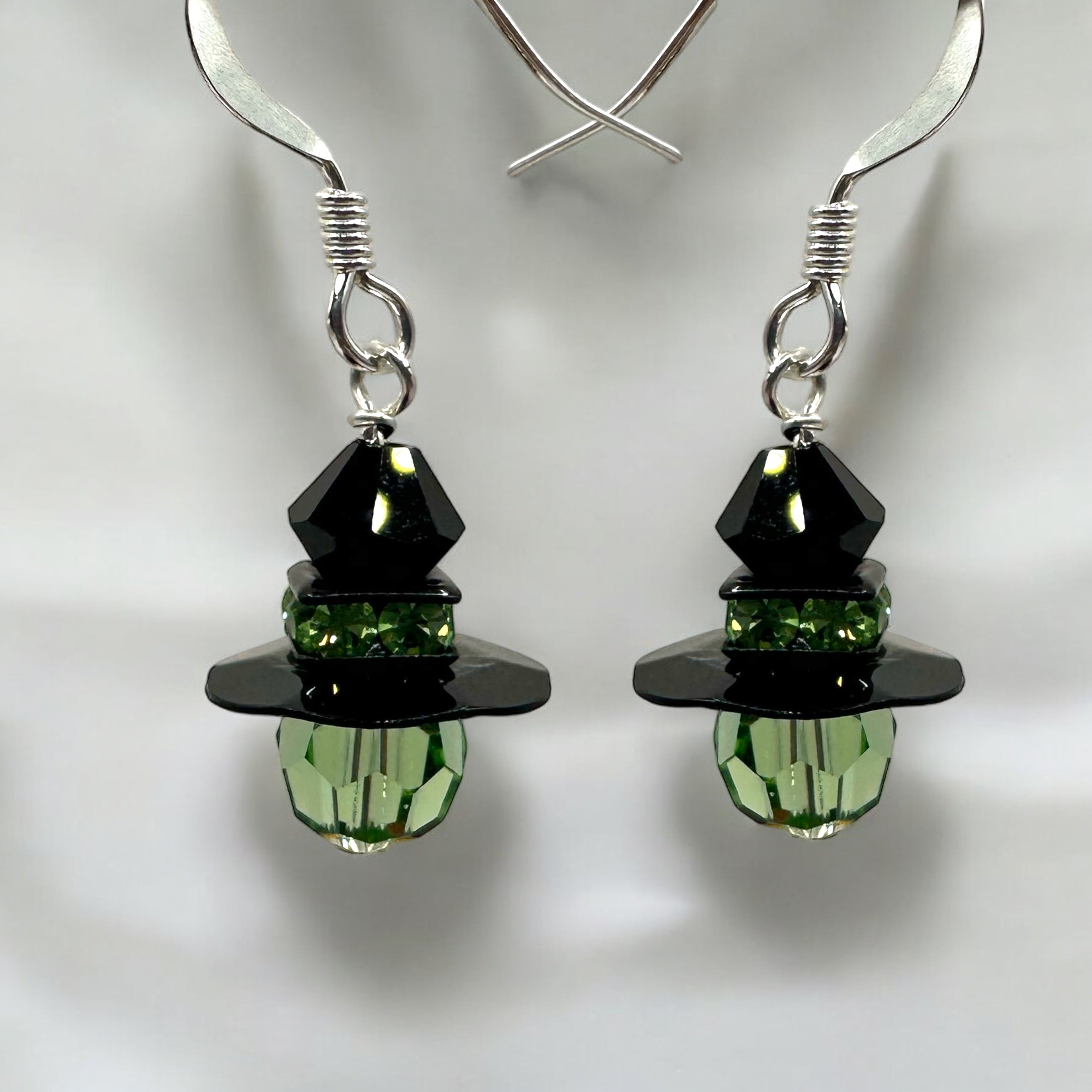 A pair of Mini Witch Halloween Earrings featuring black and green stones, crafted in silver.