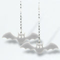 Bat-shaped earrings on silver chains against a white background