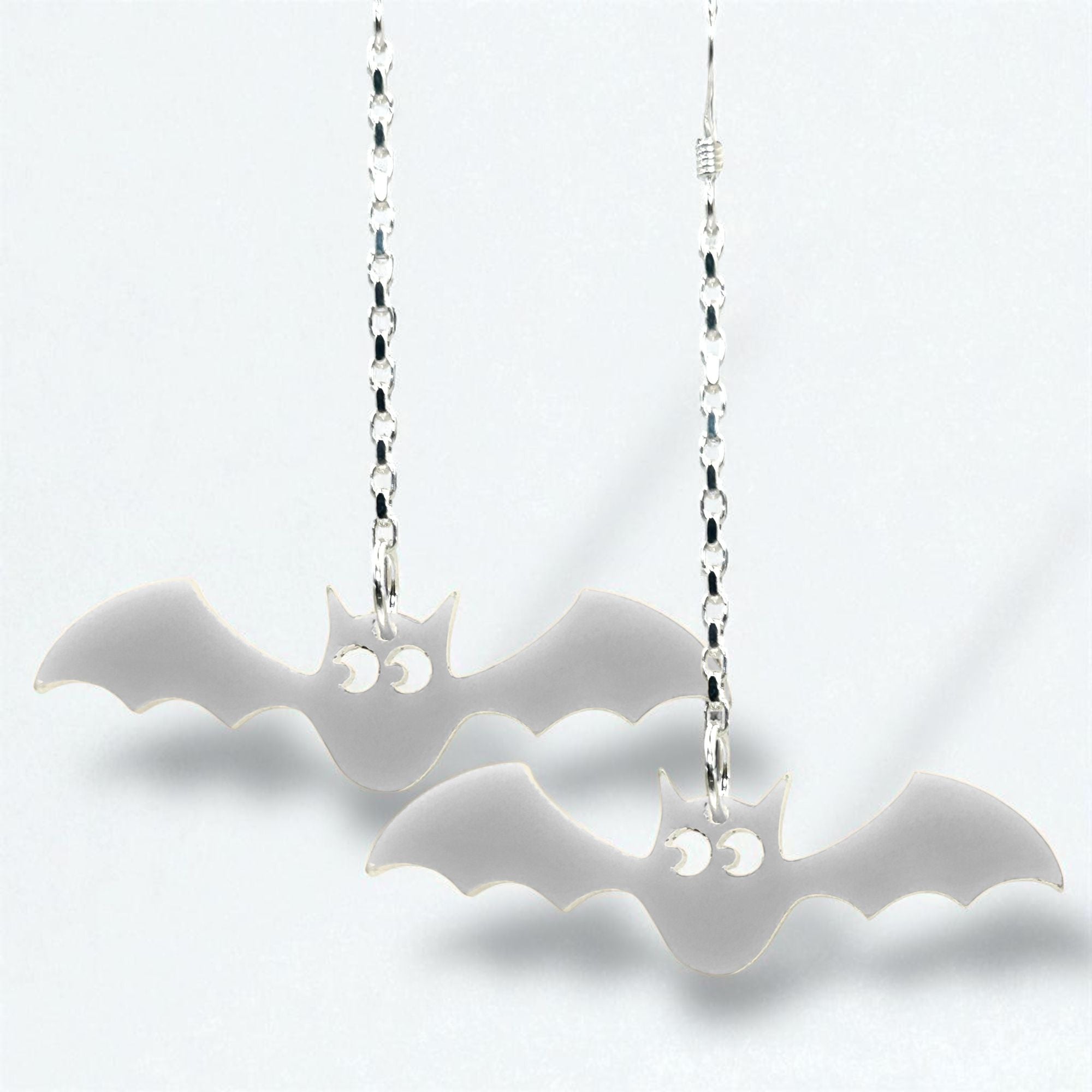 Bat-shaped earrings on silver chains against a white background