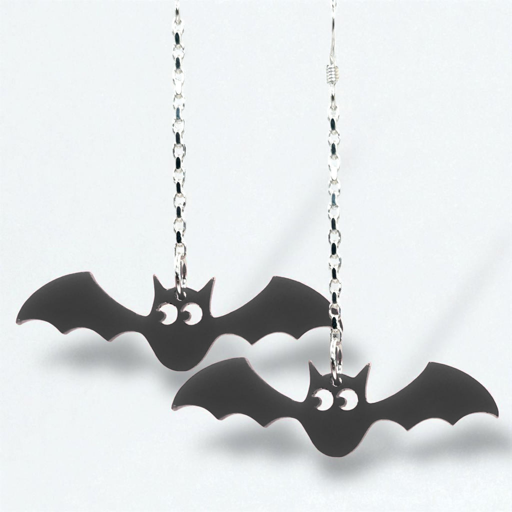 Black bat-shaped earrings on silver chains against a white background