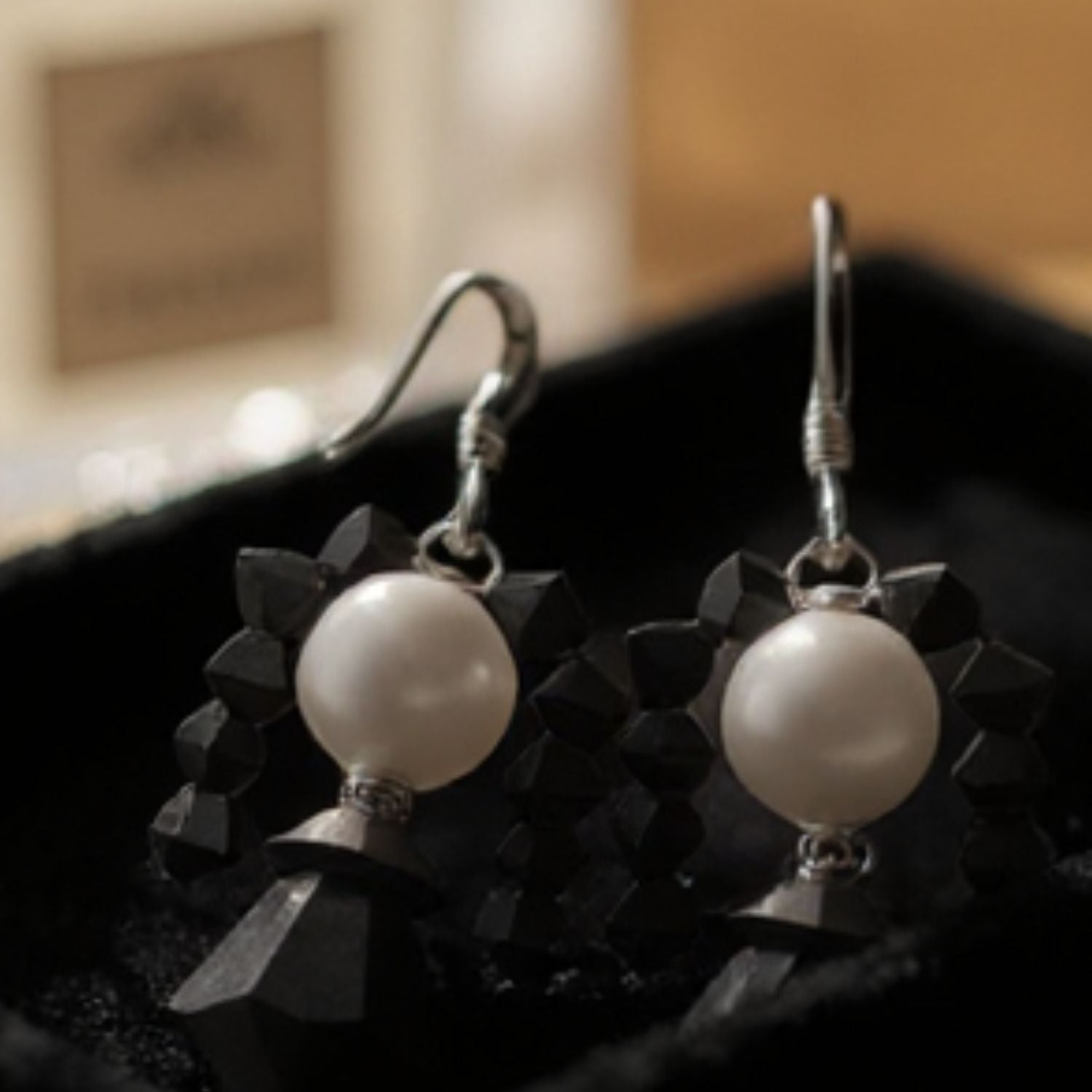 Wednesday Adams Pearl earrings with black geometric accents on a dark surface