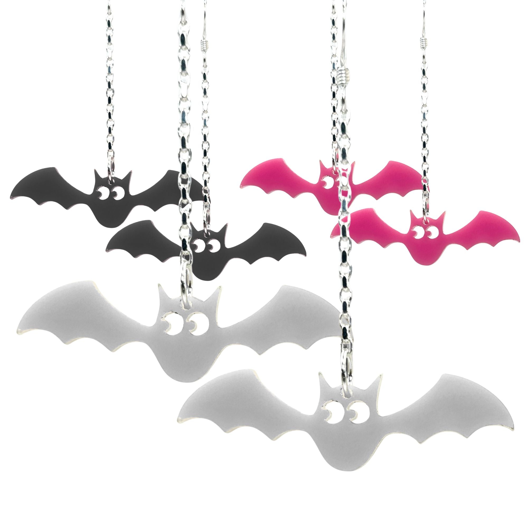 Bat-shaped earrings on chains in black, pink, and white on a white background