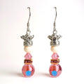 Pair of earrings with pink beads and silver crowns on a white background