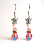 Pair of earrings with pink beads and silver crowns on a white background
