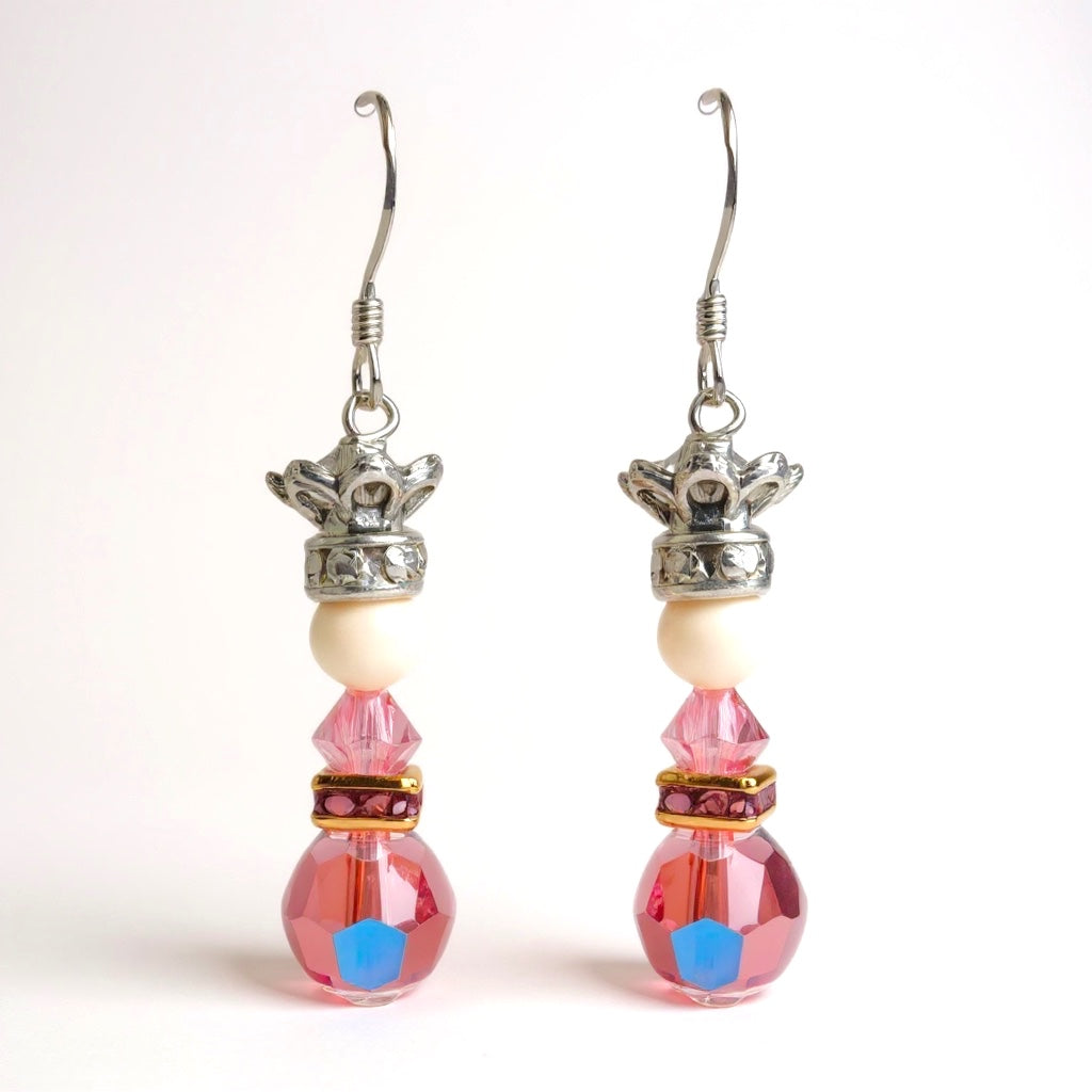 Pair of earrings with pink beads and silver crowns on a white background