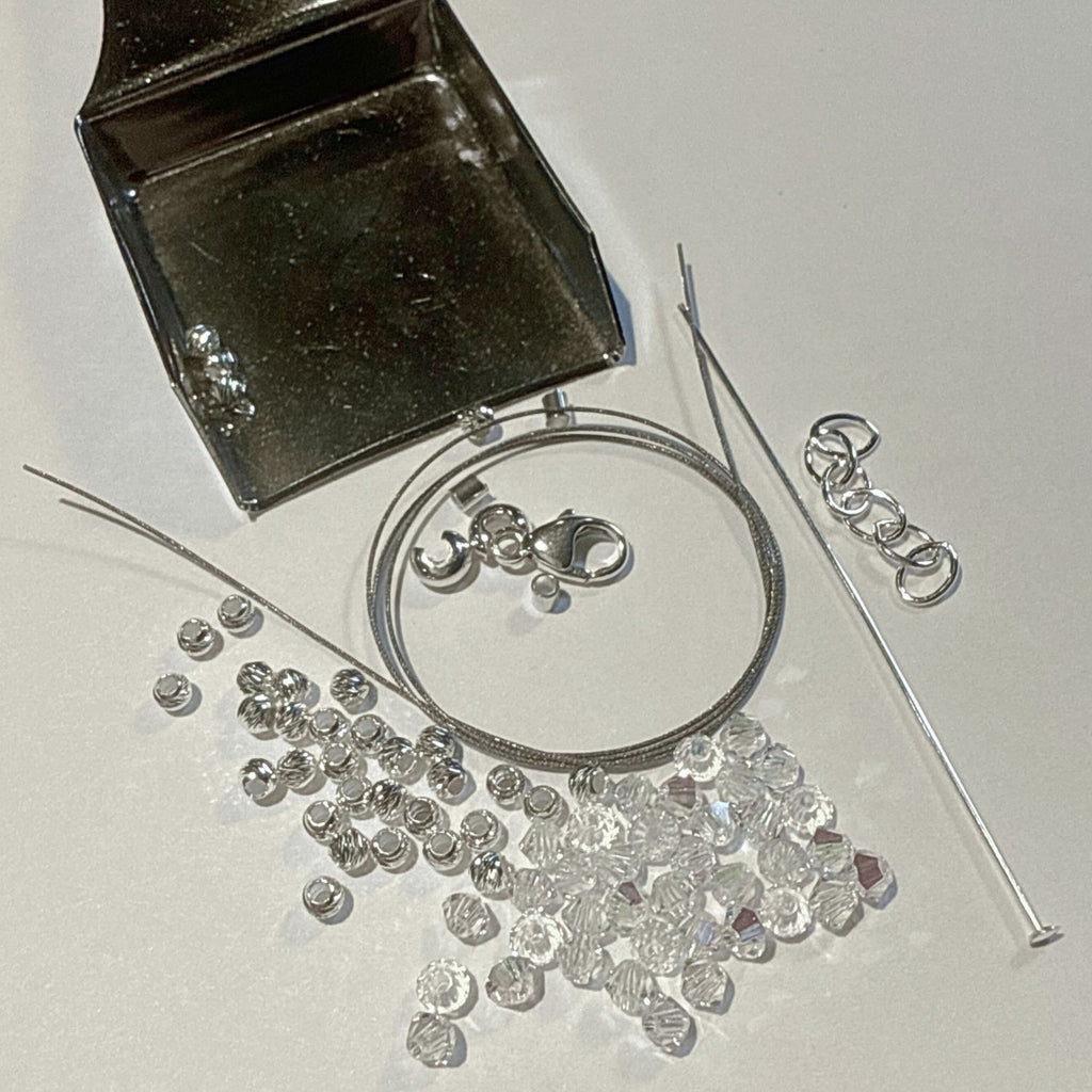 Silver jewelry components including a clasp, chain, and loose beads on a white background