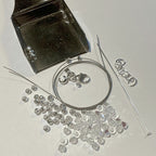 Silver jewelry components including a clasp, chain, and loose beads on a white background