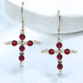 Cross-shaped earrings with red and clear beads on a white background