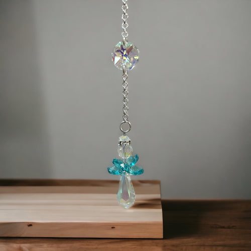 Decorative hanging angel with crystals on a wooden surface and gray background
