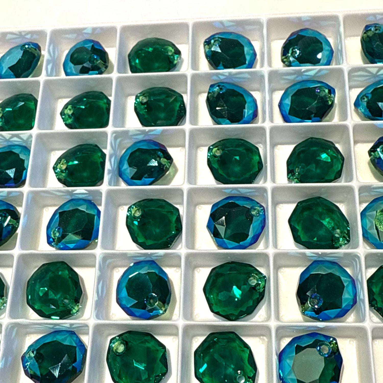 Grid of green Swarovski Majestic Pendants in a white container
