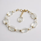 Clear crystal bracelet with gold accents on a light gray background