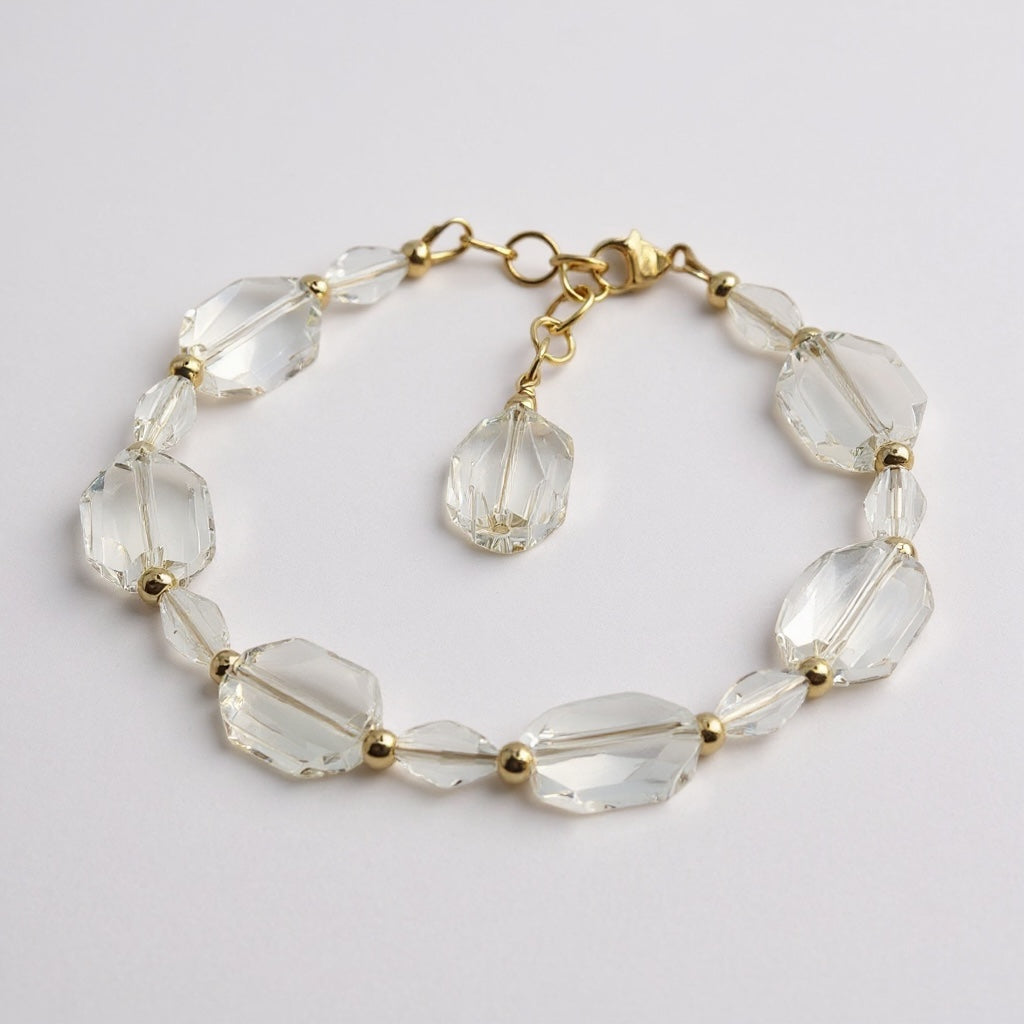Clear crystal bracelet with gold accents on a light gray background