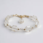 Clear beaded bracelet with gold accents on a light gray background