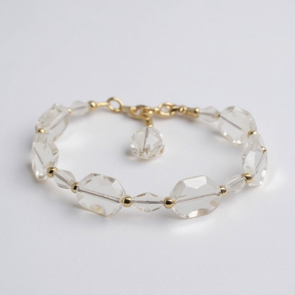 Clear beaded bracelet with gold accents on a light gray background
