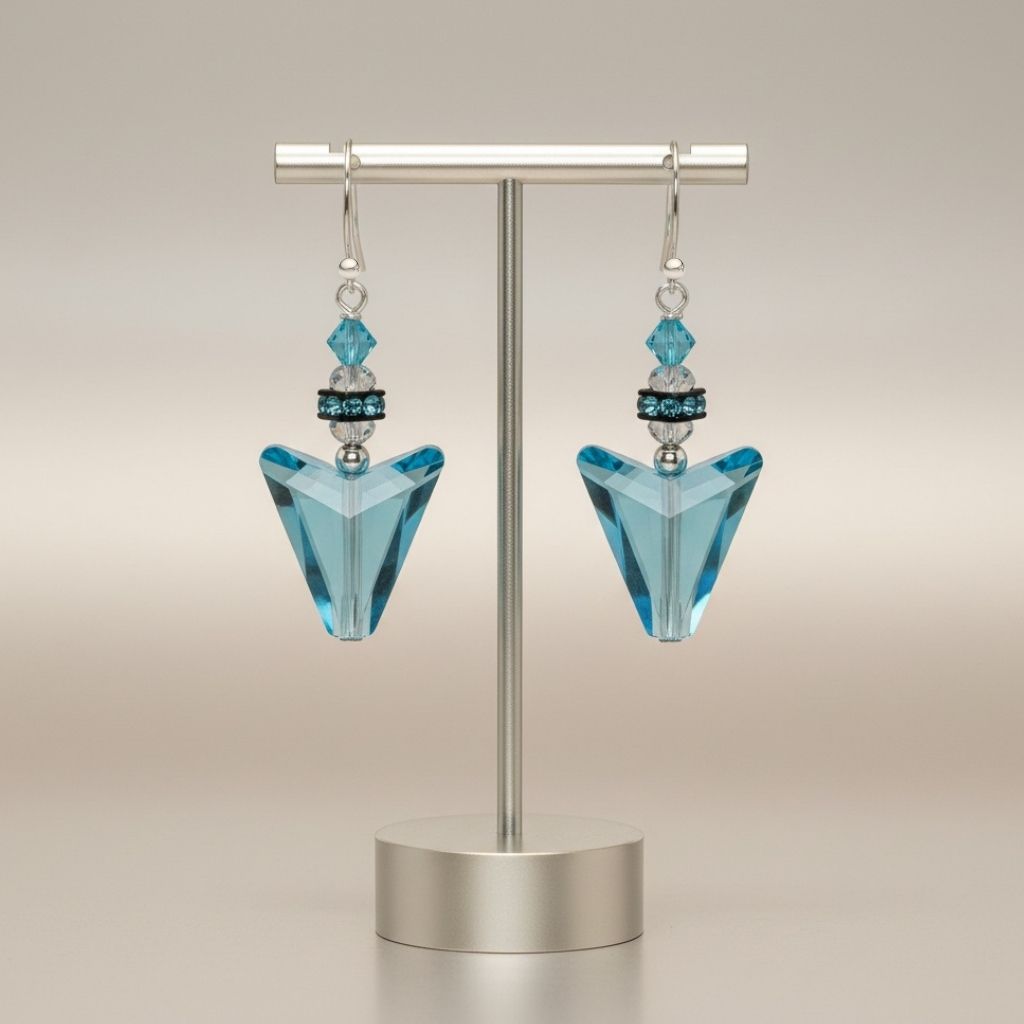 Pair of blue triangle earrings on a metallic stand against a beige background
