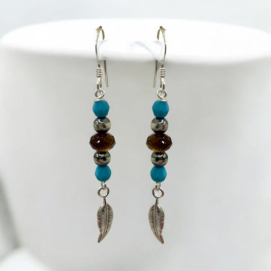 Add a touch of nature to your style with the Ready to Wear Turquoise Feather Earrings from Too Cute Beads! These handcrafted earrings feature Swarovski Mocca Briolette Beads for a warm, rich glow, paired with Sterling Silver Navajo Beads, Turquoise Swarovski Rounds, and delicate Sterling Silver Feather Charms that dangle gracefully. With a length of approximately 2 inches, these lightweight earrings offer a bohemian flair perfect for everyday wear or special occasions.