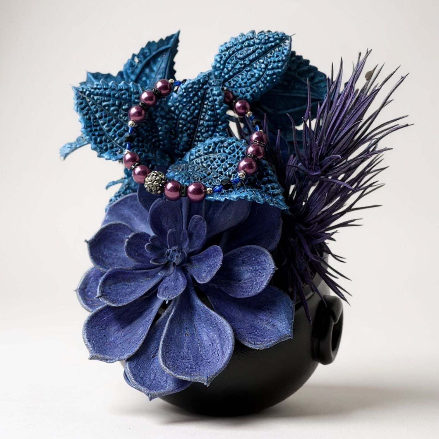 Decorative flower arrangement and bracelet with blue and purple flowers on a white background