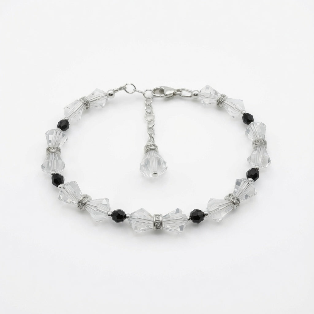A beaded bracelet featuring faceted clear crystal beads and small black beads, with silver-toned metal links and a dangling crystal charm, shown on a plain white background.