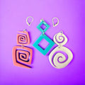 An array of acrylic earrings in pink, white, and turquoise colors with interchangeable lever-back closures, displayed on a purple background.