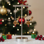 Earring display stand with decorative rudolph earrings in front of a Christmas tree.